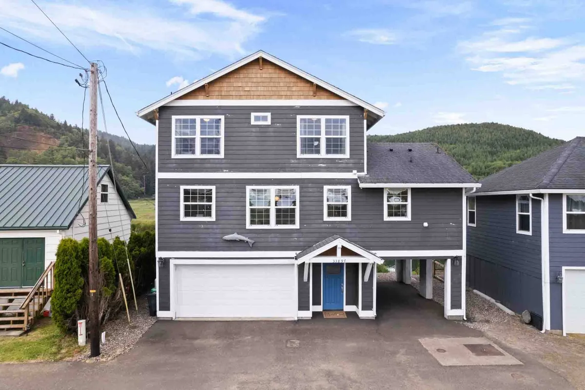 The distinctive blue front door and large windows of the home invite guests into a welcoming environment. The asymmetrical roofline and landscaped exterior hint at a modern, comfortable family retreat, with porch space ideal for morning coffee or sunset chats.
