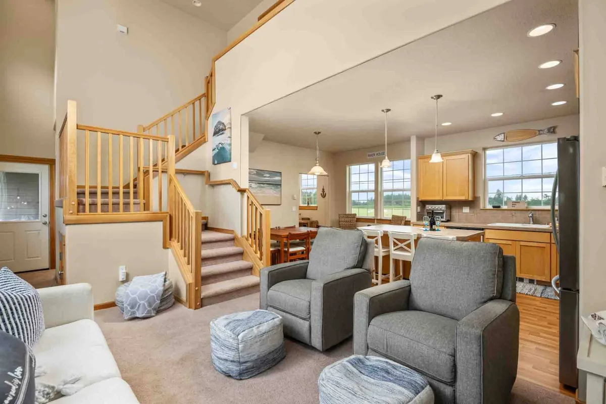 A cozy, open-plan interior encompassing the staircase, seating area, dining table, and kitchen, all within close proximity. The arrangement fosters a sense of togetherness, perfect for family gatherings, cooking, and shared meals.